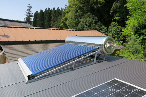 写真3:井戸小屋の屋根に乗せた真空管式太陽熱温水器と太陽光発電0.3kW(手前)